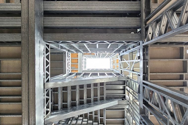 Caixa de escadas em light steel frame vista de baixo, com os perfis metálicos
              dos vários pisos alinhados.
