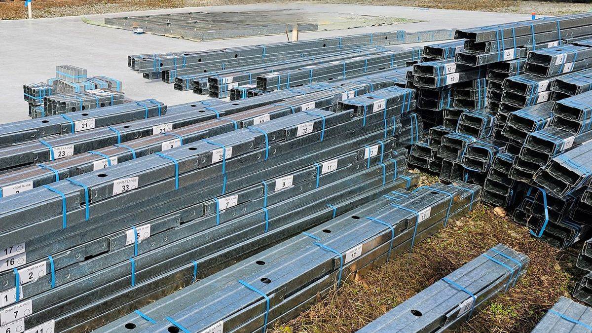 Perfis de aço galvanizado em light steel frame empilhados em paletes, no
              estaleiro, prontos para montagem.